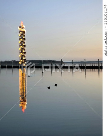 A glowing tower with a spiral staircase reflecting off the calm waters of Lake Goitzsche. A glowing tower with a spiral staircase reflecting off the calm waters of Lake Goitzsche. 136102174