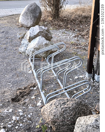 An empty metal bicycle rack next to decorative boulders 136102189