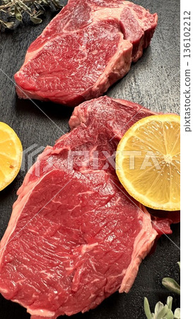Uncooked Steak Paired With Citrus And Herbs For Attractive Presentation, Freshly Cut Raw Steaks Enhanced By Lemon Halves And Fragrant Herbs For Visual And Flavor Appeal Uncooked Steak Paired With Citrus And Herbs For Attractive Presentation, Freshly Cut Raw Steaks Enhanced By Lemon Halves And Fragrant Herbs For Visual And Flavor Appeal 136102212