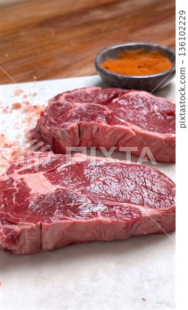 Two Strip Steaks With Smoked Paprika And Herb Sprigs On Marble, Chef Tasting Prep For Tasting Menu, Refined Seasoning And Precise Portioning, Elevated Restaurant Ambiance 136102229