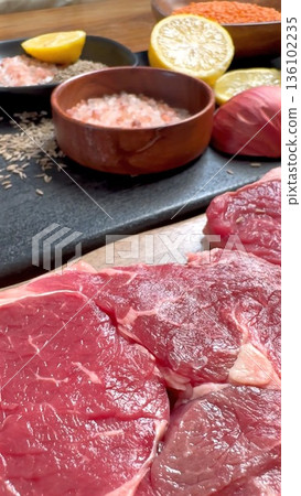 Beef Served With Lemon And Onions, Uncooked Steak Accompanied By Citrus And Onion Decor, Fresh Raw Beef Combined With Lemon Slices And Onion Garnishes On Slate Plate 136102235