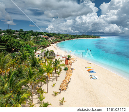 Aerial view of sandy beach, palm trees, umbrellas, boats, sea 136102252