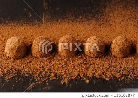 Cocoa dusted chocolate truffles in a row with reflection on black background 136102877