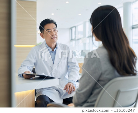 Female patient listening to doctor's explanation in examination room 136103247