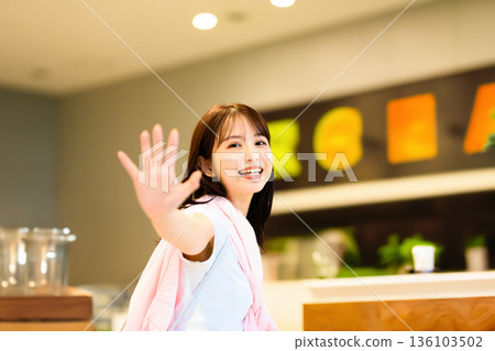 A woman waving a hand 136103502