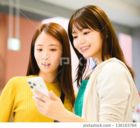 Two women looking at a smartphone ■ Photo courtesy: Kansai International Airport (KIX) 136103764