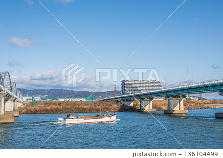 淀川上的輸水橋和枚方橋。一艘採砂船逆流而上。從枚方市方向拍攝的景色。 淀川上的輸水橋和枚方橋。一艘採砂船逆流而上。從枚方市方向拍攝的景色。 136104499