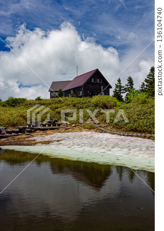 Mount Aizu-Koma with remaining snow, Komanoike Pond and Komano Hut 136104740