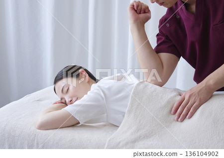 Female masseuse giving back massage Female masseuse giving back massage 136104902