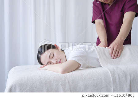 Female masseuse giving back massage Female masseuse giving back massage 136104905
