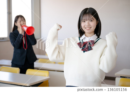 一名女學生揮舞著拳頭，一位老師在一旁為她加油。 136105156