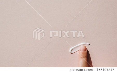 指尖沾著一點保養霜,背景是淺粉色。 指尖沾著一點保養霜,背景是淺粉色。 136105247