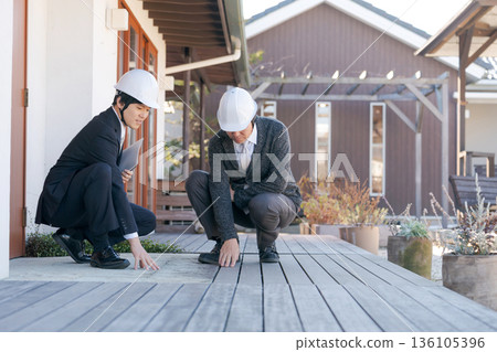 A man inspecting a wooden deck 136105396