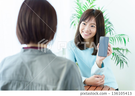 A woman showing a smartphone screen 136105413