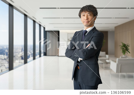 一位商人雙手交叉放在胸前,身處一間漂亮的辦公室。 一位商人雙手交叉放在胸前,身處一間漂亮的辦公室。 136106599