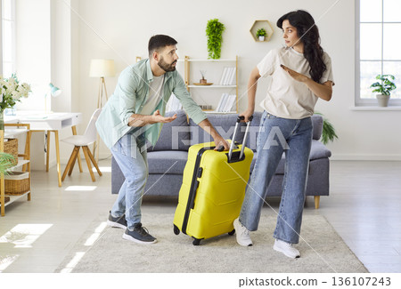 Couple arguing at home as woman packs suitcase to leave, relationship conflict 136107243
