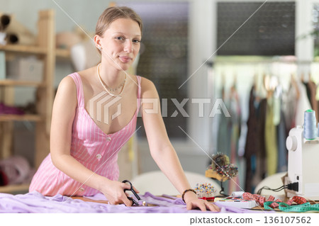 Woman seamstress cutting fabric in sewing workshop Woman seamstress cutting fabric in sewing workshop 136107562