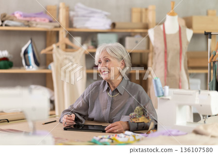Mature dressmaker drawing sketch on tablet Mature dressmaker drawing sketch on tablet 136107580