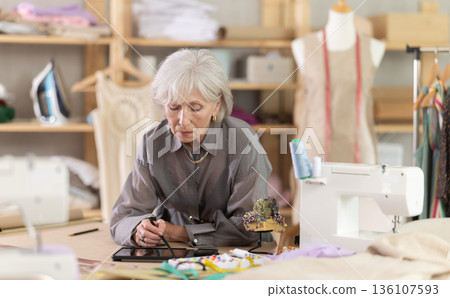 Woman dressmaker makes pattern using tablet Woman dressmaker makes pattern using tablet 136107593