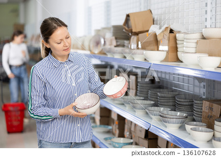 Smiling woman choosing ceramic ramen bowls in Asian store 136107628