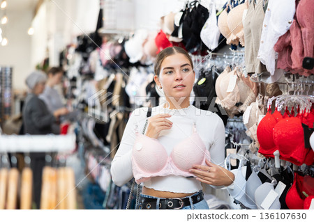 Young woman choosing pretty bra in underwear store 136107630