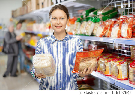Woman in supermarket buys daily groceries, pasta Chinese noodles Woman in supermarket buys daily groceries, pasta Chinese noodles 136107645