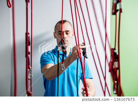 Physiotherapy. Suspension training therapy. Young man doing fitness traction Physiotherapy. Suspension training therapy. Young man doing fitness traction 136107673