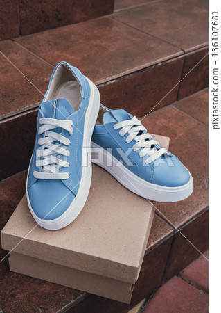 Elegant blue leather womens shoes blank product for branding displayed on recycled cardboard box. New casual female sneakers no-brand footwear e-commerce. No logo product unbranded fashion 136107681