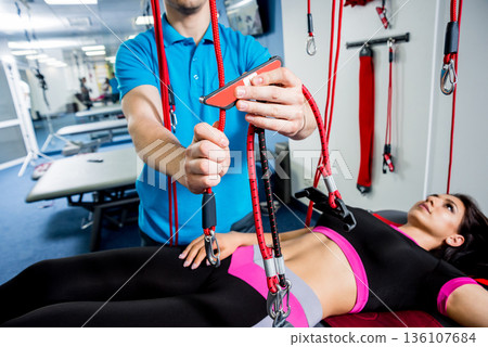 Physiotherapy. Suspension training therapy. Young woman doing fitness traction Physiotherapy. Suspension training therapy. Young woman doing fitness traction 136107684