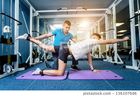Rehabilitation therapy. Young man doing exercises on mat  136107686