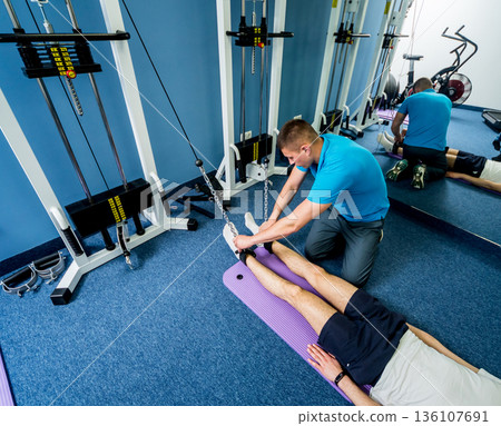 Rehabilitation therapy. Young man doing exercises on mat  136107691