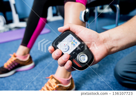 Physical therapist install electrostimulator on the muscles of the legs. Physical therapist install electrostimulator on the muscles of the legs. 136107723
