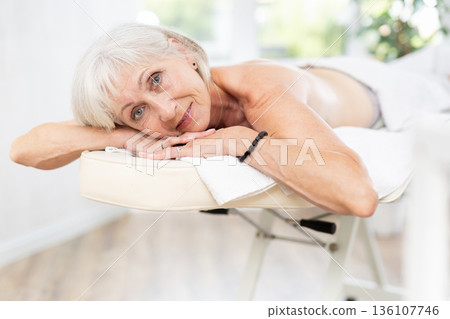 Mature female client of massage parlor lies with legs covered with towel Mature female client of massage parlor lies with legs covered with towel 136107746