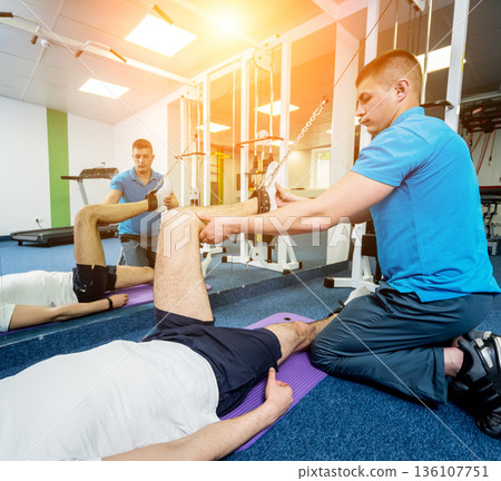 Rehabilitation therapy. Young man doing exercises on mat Rehabilitation therapy. Young man doing exercises on mat 136107751