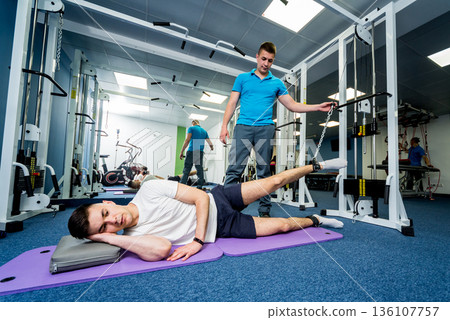 Rehabilitation therapy. Young man doing exercises on mat Rehabilitation therapy. Young man doing exercises on mat 136107757