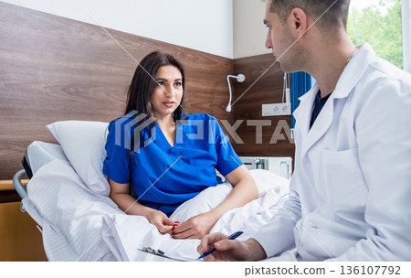 Traumatologist talking with young female patient in modern hospital Traumatologist talking with young female patient in modern hospital 136107792