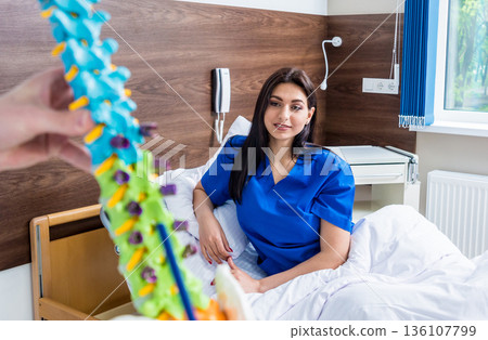 Orthopedist showing spine model to patient in hospital 136107799
