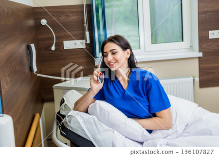 Patient talking on the phone in hospital bed. Young caucasian woman. Patient talking on the phone in hospital bed. Young caucasian woman. 136107827