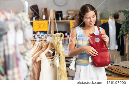 Happy young woman choosing handbag in clothing store 136107900