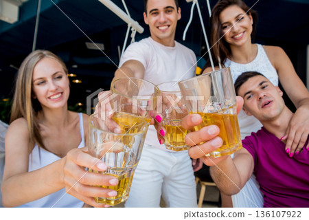 Cheerful friends in the pub. Drinking beer, talking, having fun. 136107922