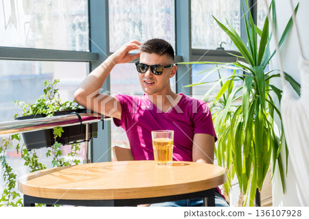 Young man in the pub. Drinking beer, eating pizza. 136107928