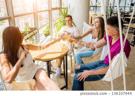 Cheerful friends in the pub. Drinking beer, talking, having fun. 136107944