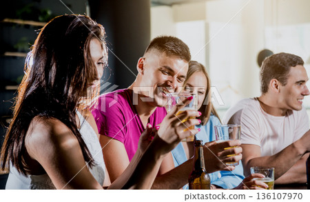 Cheerful friends in the pub. Drinking beer, wine and whisky 136107970