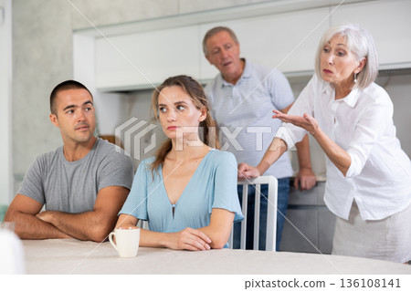 Elderly parents make claims to young couple in kitchen 136108141