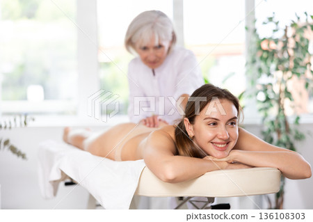 Young woman clinet satisfied with work of masseuse Young woman clinet satisfied with work of masseuse 136108303