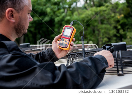 Technician use hand-held anemometer measuring air flowing measurement 136108382
