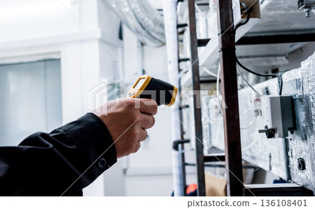 Technician use infrared thermal imaging camera to check temperature at fuse-box Technician use infrared thermal imaging camera to check temperature at fuse-box 136108401