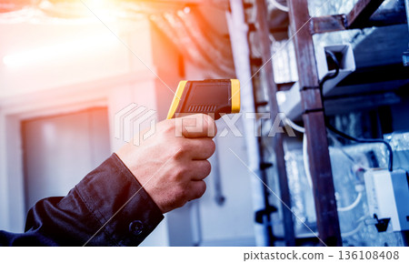 Technician use infrared thermal imaging camera to check temperature at fuse-box Technician use infrared thermal imaging camera to check temperature at fuse-box 136108408