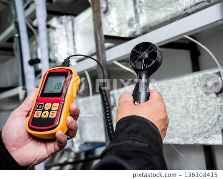 Technician use hand-held anemometer measuring air flowing measurement 136108415