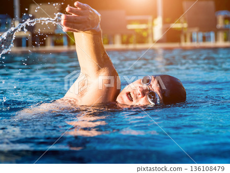 Young athletic man swimming in the swimming pool 136108479